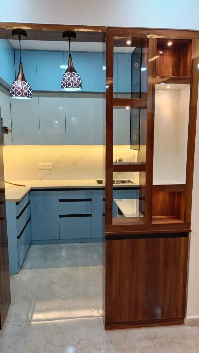Blue modular kitchen framed by a glossy wood partition with display niches and pendant lights