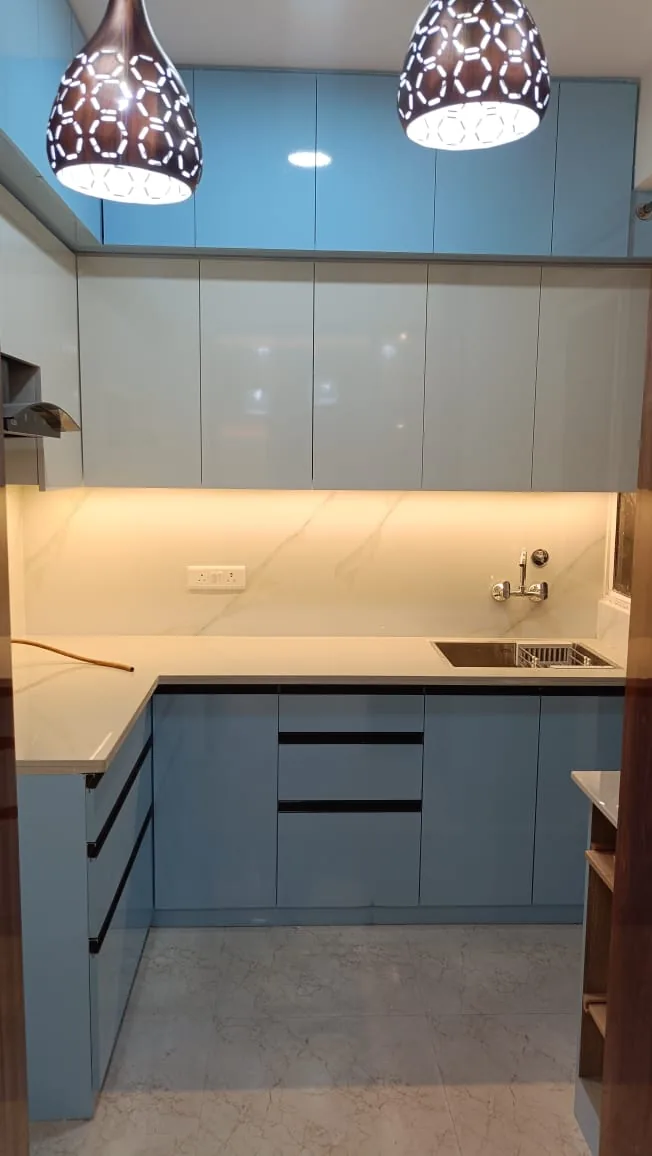 Compact blue and white modular kitchen with handleless cabinetry and warm under-cabinet lighting