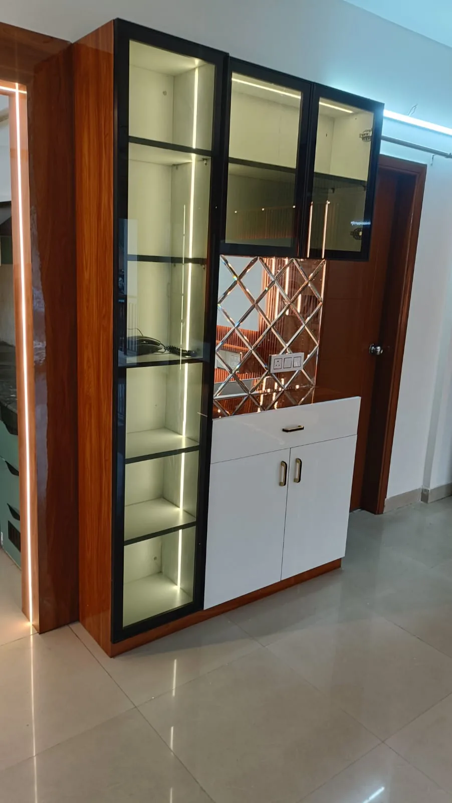 Compact custom display and storage unit with warm wood side panel, glass cabinet and white base storage
