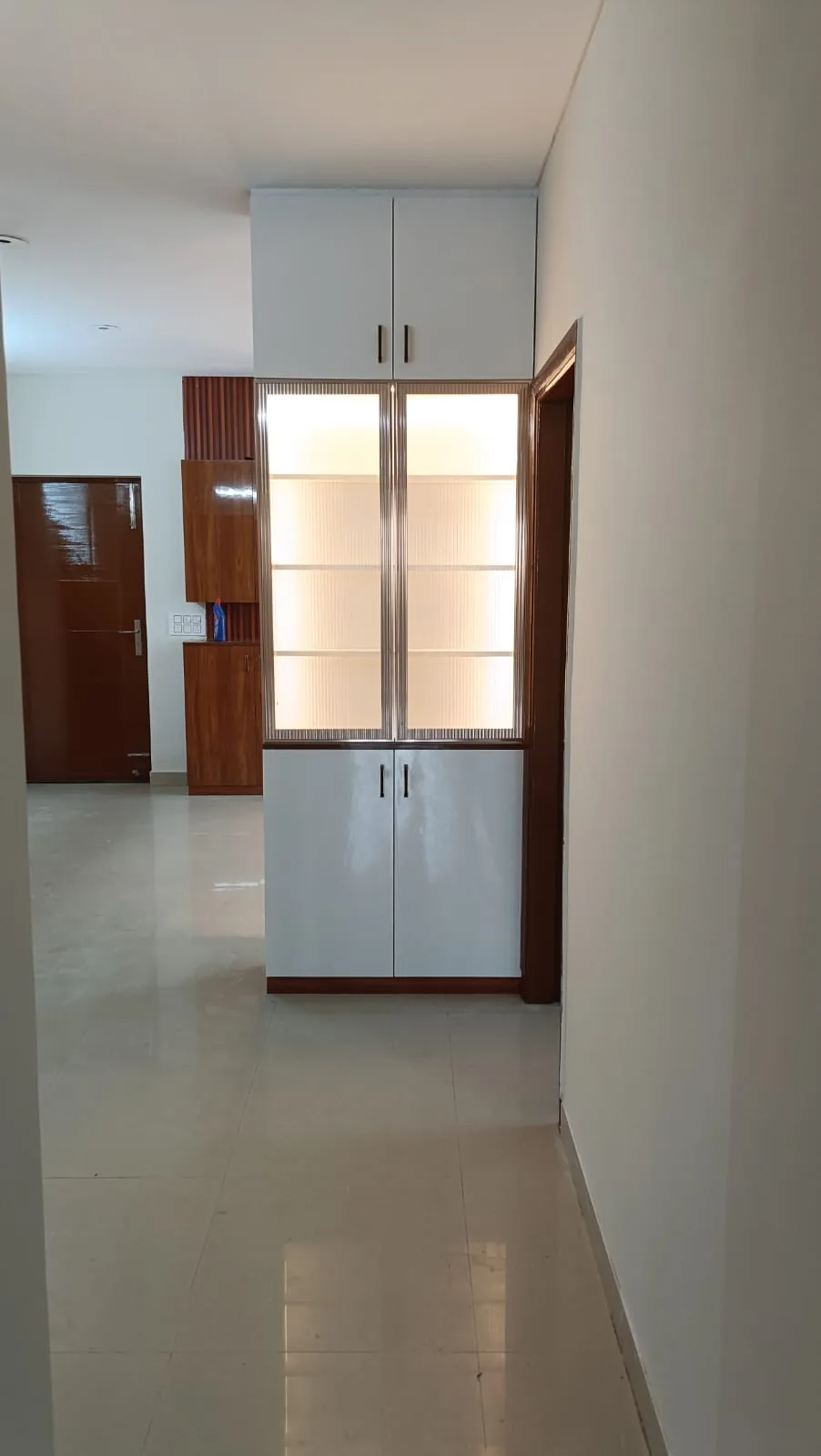 Tall white storage unit with illuminated fluted glass display doors