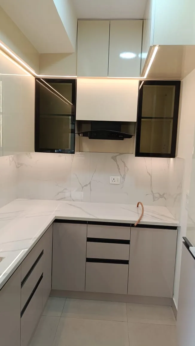 Compact light grey modular kitchen with marble-look countertop and black framed glass cabinets
