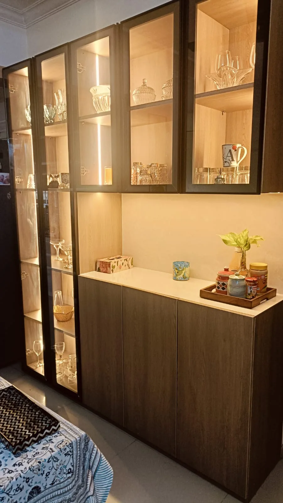 Warm illuminated crockery and display cabinet with glass shutters and dark wood base storage