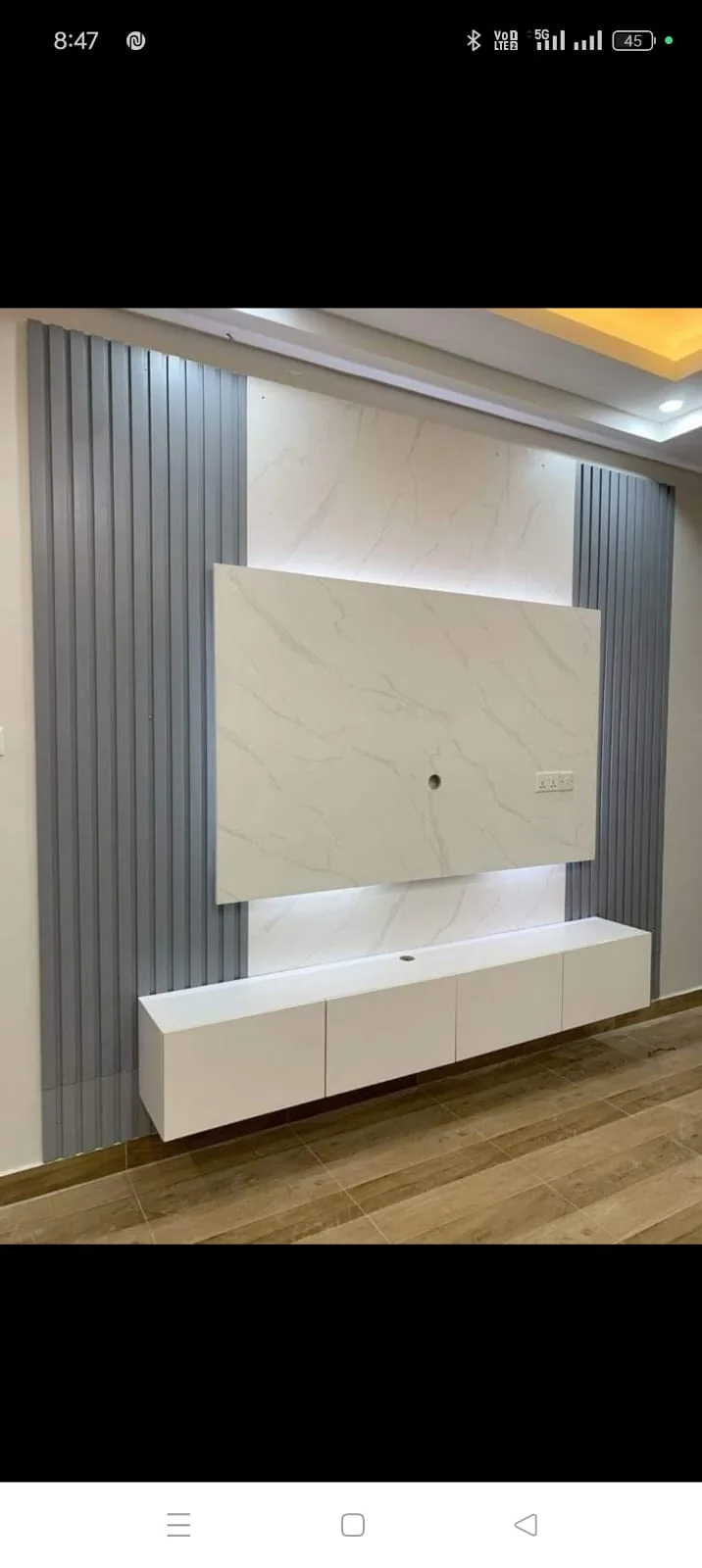 Minimal white marble-look TV wall with grey vertical slats and floating console