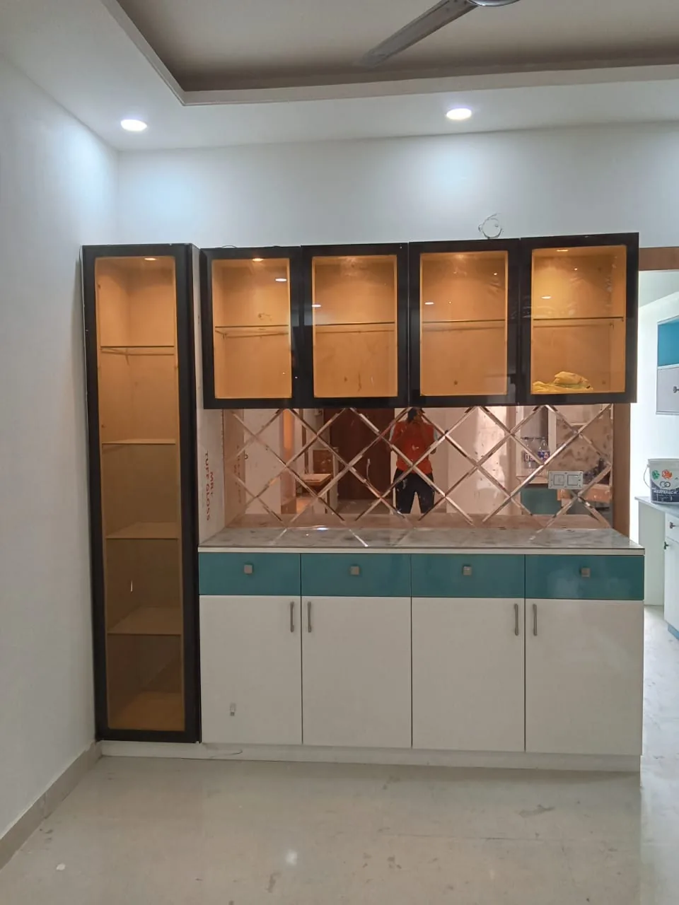 Crockery cabinet with teal drawers, mirrored backsplash and black framed glass storage