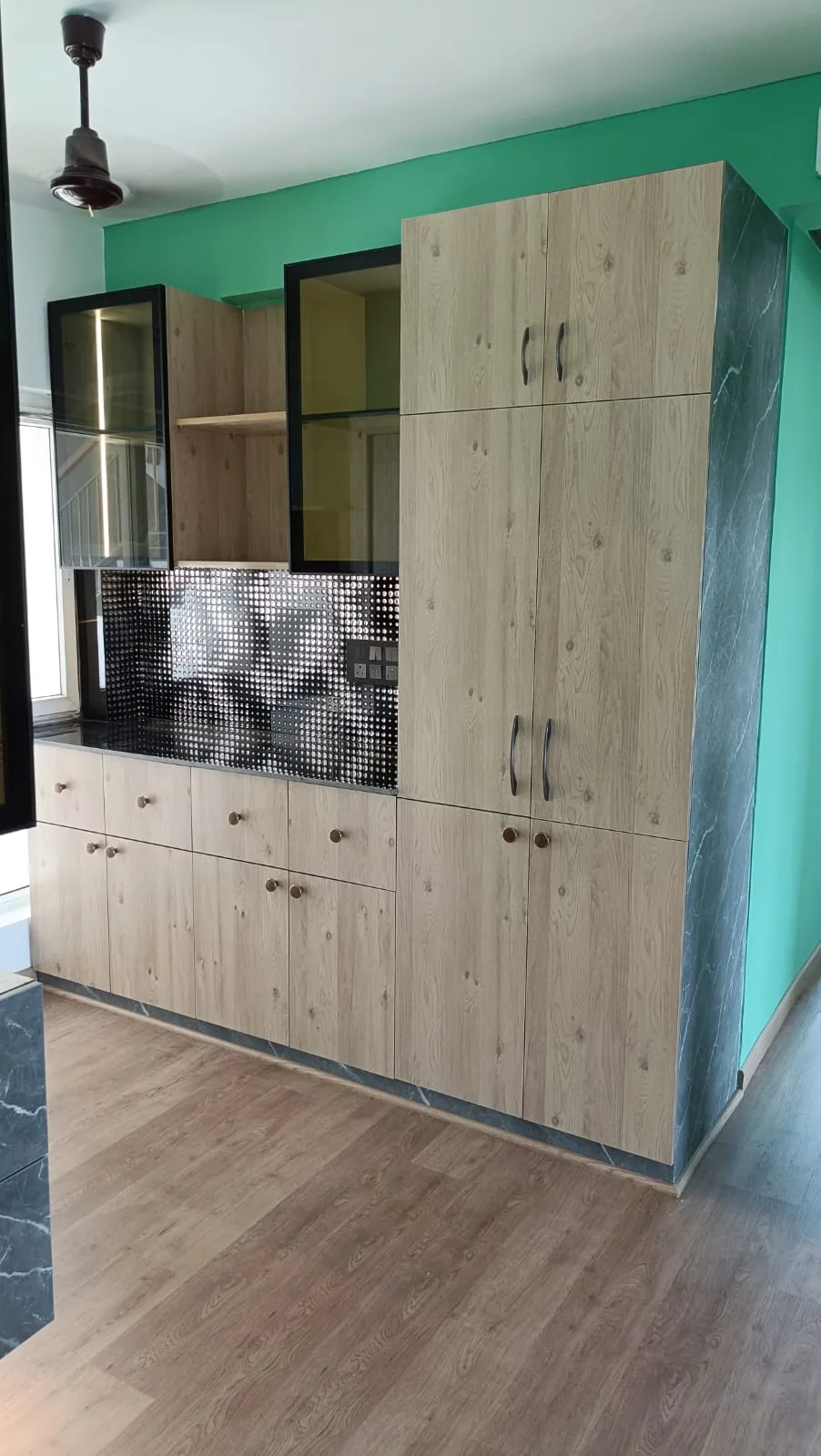 Custom modular kitchen with wood-finish tall storage and black framed glass cabinets