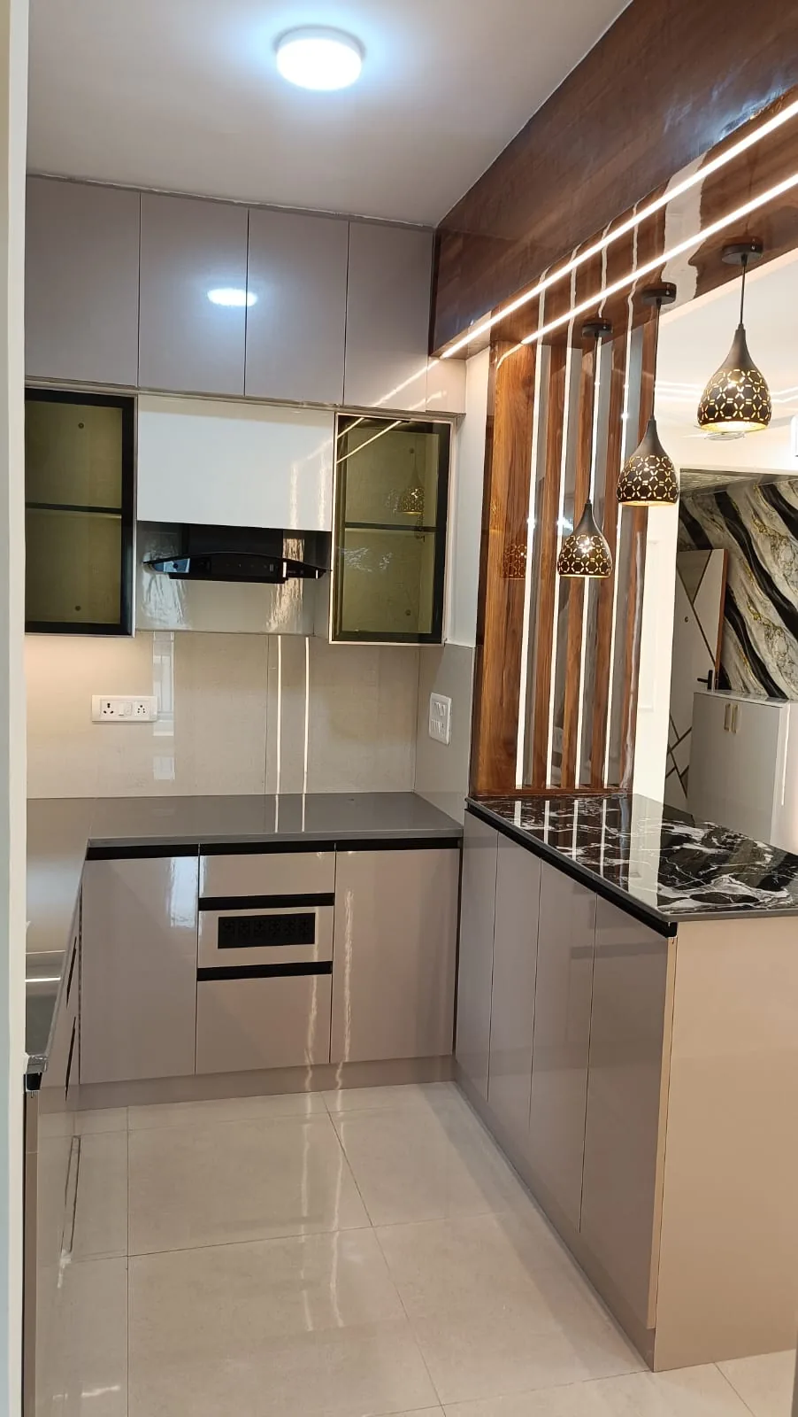 U-shaped modern kitchen with taupe cabinetry, black stone breakfast ledge and wood slat partition